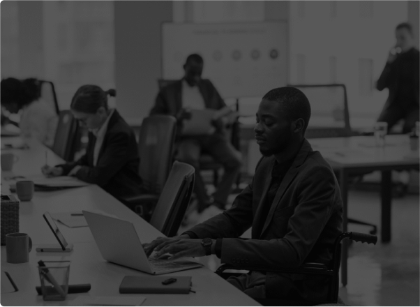 Black and white photo of professionals working on laptops in an open office