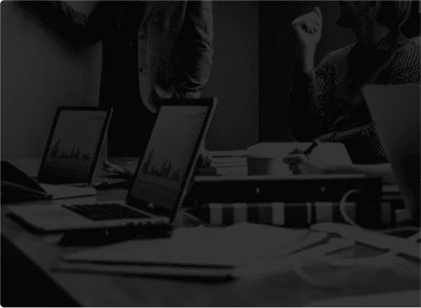 Black and white photo of a strategy meeting with laptops open on the table