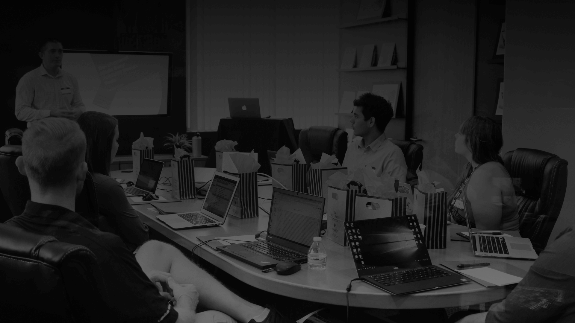 A team meeting around a conference table with laptops open